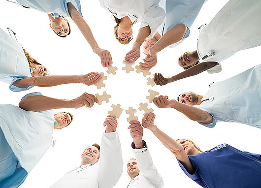 Medical Team Joining Jigsaw Pieces In Huddle